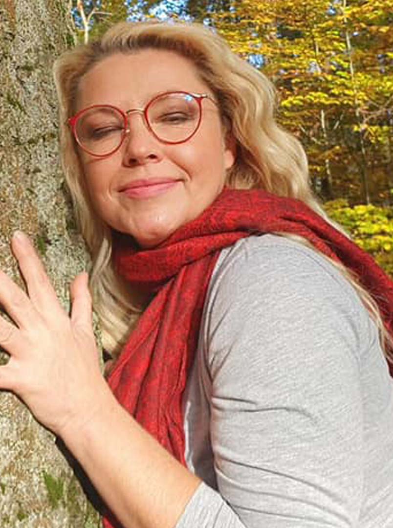 Anna Vanessa w plenerze, w czerwonych okularach i szalu, przy drzewie